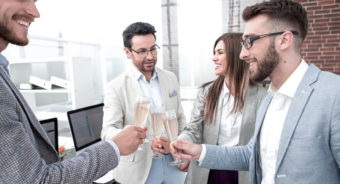 business team raises glasses of champagne in the office e1667459662573 - Cómo utilizar tecnología en eventos corporativos de menos de 100 empleados